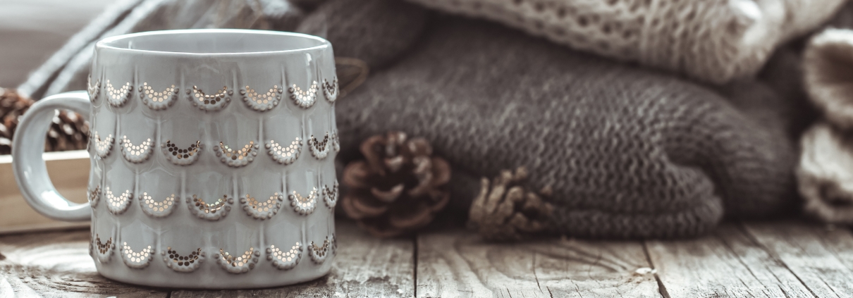 Gemütliche Details wie Tasse, Wollpullis, Tannenzapfen im Wohnzimmer